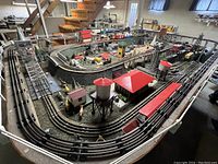 Overall view of train layout on wooden table with multiple track loops, buildings, and locomotives