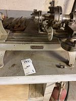 Overall view of lathe machine on workbench with tools and motor visible.