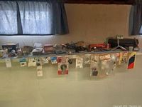 Wide shot of metal shelf with assorted model airplane parts and tools including packaged parts hanging on front edge and larger boxed parts on top.