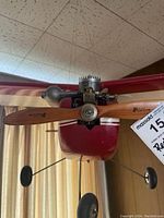 Close-up of the front of the red model airplane showing wooden propeller, engine details and landing gear wheels.