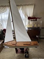 Assembled wooden sailboat model with sails and stand