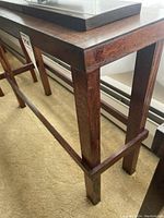 Close-up of dark mahogany table/stand showing frame and legs structure.
