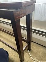 Close-up of the dark brown mahogany wood table/stand frame showing the legs and side supports.