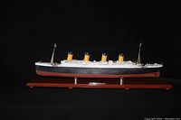 Front view of assembled Titanic model in display case on wooden base against black background