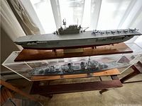 Wide view of the aircraft carrier model on wooden base, enclosed in a plexiglass case, showing details of the miniature ship and aircraft on deck.
