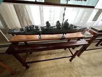 Full view of the U.S. Navy ship model in clear Plexiglass case on a wooden stand.