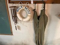 Wall mounted wooden wind chime, life ring with 'BALA MIST' and green fisherman's suit hanging