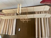 Front view of the large wooden skeletal frame airplane model showing the fabric covered wings and fuselage structure.