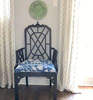 Black wooden armchair with pagoda-style top rail, fretwork back and blue and white floral seat cushion