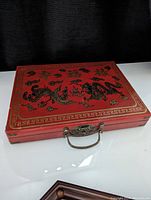 Closed red wooden Mahjong case with black and gold dragons and Chinese characters.