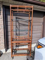 Full front and side view of vintage Chinese Chippendale style rattan and bamboo etagere showing overall structure, shape, and casters.