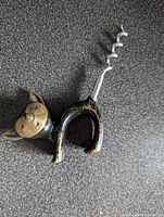 Top view of the brass cat corkscrew showing the black painted body with wear and the brass face.