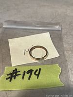 Photo of a 14K gold band ring on a clear plastic bag with a handwritten label showing '14K' and '#194'.