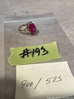 Top view of ring in plastic bag showing oval red stone and prong setting