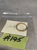 Single 14 karat gold band ring inside a plastic bag with handwritten notes indicating 14K and item #195.