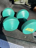 Photo of two green 10 lbs dumbbells lying on a dark surface showing their shape and weight markings.