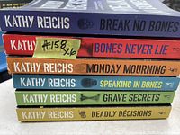 Stack of six Kathy Reichs books showing titles and authors on spines.