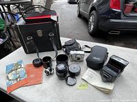 Overview of lot showing lenses, camera, flash, bag, and manuals on table