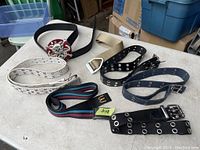 Lot of 8 men's belts displayed on a table, showing variety of colors and buckle styles.