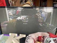 Large LG plasma TV powered on with 'No Signal' message visible on screen, surrounded by various items.