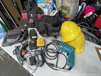 Lot overview showing power tools, batteries, tool pouches, and hard hats all visible on workbench