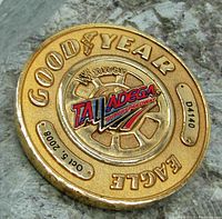 Close-up image of one gold-tone winner's coin from Oct 5, 2008 showing Goodyear Eagle branding, Talladega Superspeedway logo and serial number D4140.
