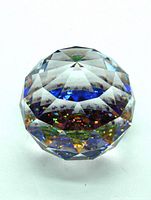 Faceted crystal gazing ball showing colorful light refraction and clear geometric cuts.