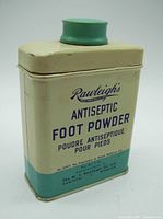Front view of a cream and green vintage metal tin labeled Rawleigh's Antiseptic Foot Powder with product and brand details.