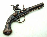 Front view of vintage flintlock style toy cap pistol showing curved grip and detailed metal engravings