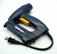 Electric stapler and brad nailer tool in dark blue with yellow trigger and attached power cord visible, showing overall tool condition and design.