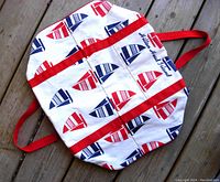 Front view of the nautical-themed tote bag with red and blue sailboat prints and red straps.