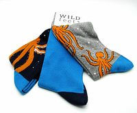 Three pairs of colorful Wild Feet socks showing kraken/octopus designs and solid colors, folded with label visible.