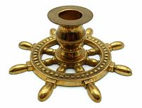 Angled close-up of a brass ship's wheel candle holder showing central circular candle placement and eight spokes