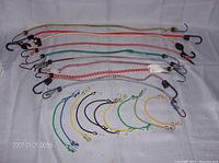 Overview of all 20 bungee cords laid out with thicker cords on top and thinner cords below, showing multiple colors and hooked ends.