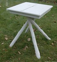White handcrafted Adirondack style wooden table with square top and four angled legs on grass.