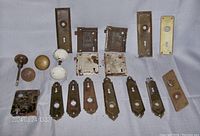 Overview of all antique door hardware pieces including mortise locks, keyhole plates, and door knobs arranged on a flat surface.