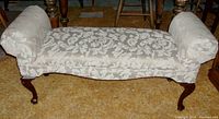 Frontal angled view showing the floral fabric upholstery and Queen Anne wooden legs of the bench.