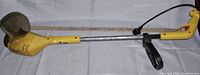 Full length photo of a yellow MCCULLOCH Eager Beaver electric string trimmer showing the entire tool from motor housing, shaft, handle, to guard.