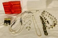 Full view of all jewelry items displayed with red gift box, includes necklaces, earrings on card and loose, bracelets including decorative one.