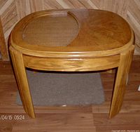 Front view of oak side table showing the oval top with rattan inset and solid wooden section along with four legs.