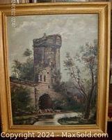 Photo of the entire framed oil on board painting showing the stone tower and surrounding trees under cloudy sky, with visible artist signature and gold finish wood frame.