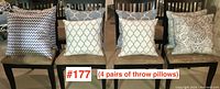Four pairs of throw pillows shown on chairs, various patterns including spotted, geometric, and paisley