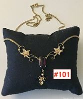 Full view of necklace laid on black display pillow showing chain, floral motifs, central stone and drop