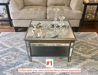 Frontal view of square coffee table showing mirrored top, silver frame and lower shelf