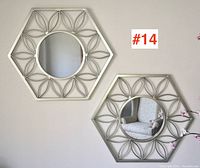 Pair of silver tone hexagonal contemporary wall mirrors mounted on a wall, showing their full decorative metal frames and round mirrors.