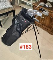 Full view of set of golf clubs in black stand bag with legs extended.