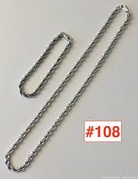 Full view of the sterling silver necklace and bracelet set laid flat on a white surface to show length and style.