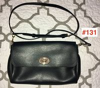 Front view of black leather Coach crossbody bag with adjustable shoulder strap laid flat