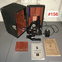 Full lot items displayed including microscope, case, power adapter, manuals, and wooden box.