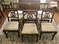 Front view of all six walnut dining chairs arranged on floor rug